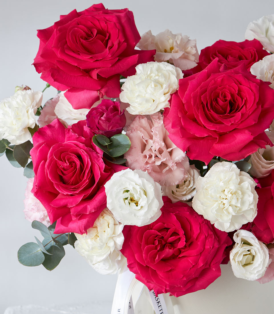 Deep red and pink roses with white lisianthus in a luxury gift flower box, eucalyptus greenery included