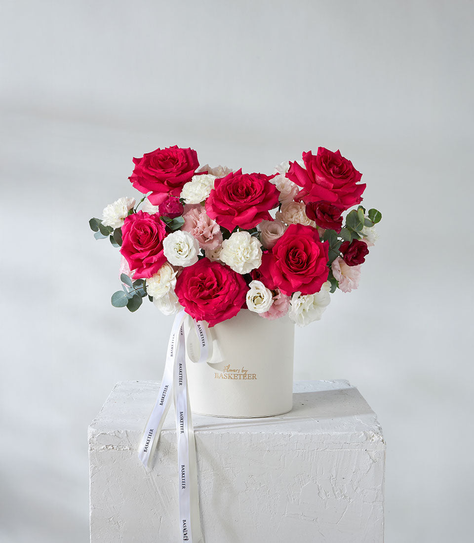 Premium red roses and white lisianthus in luxury white box with gold-foil branding