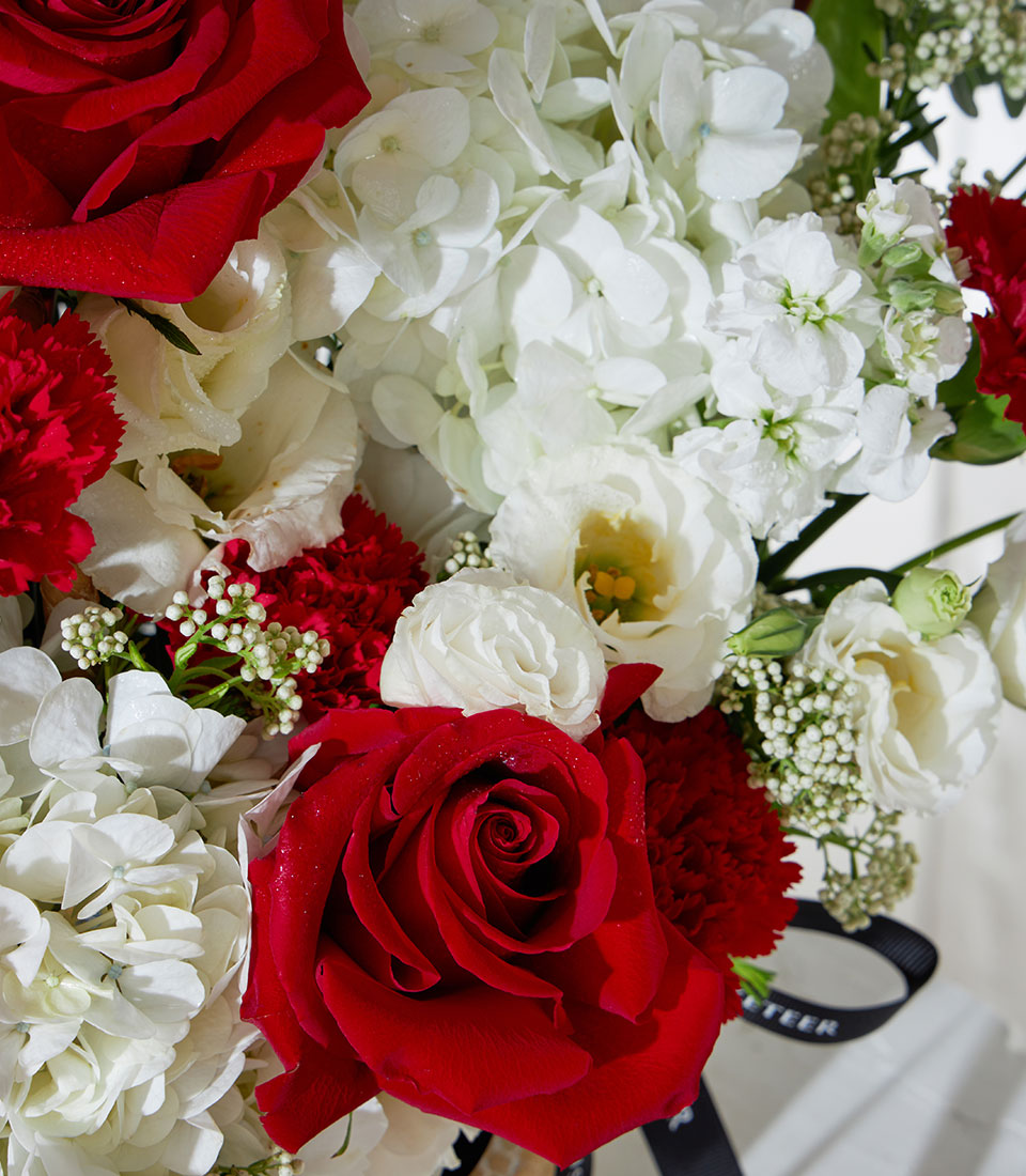 Red roses and white hydrangea arrangement in luxury gift basket with premium florals