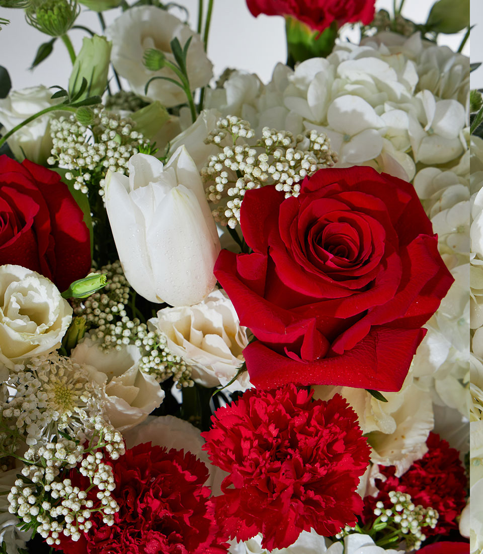 Red and white roses with hydrangea and lisianthus in a fresh luxury flower basket