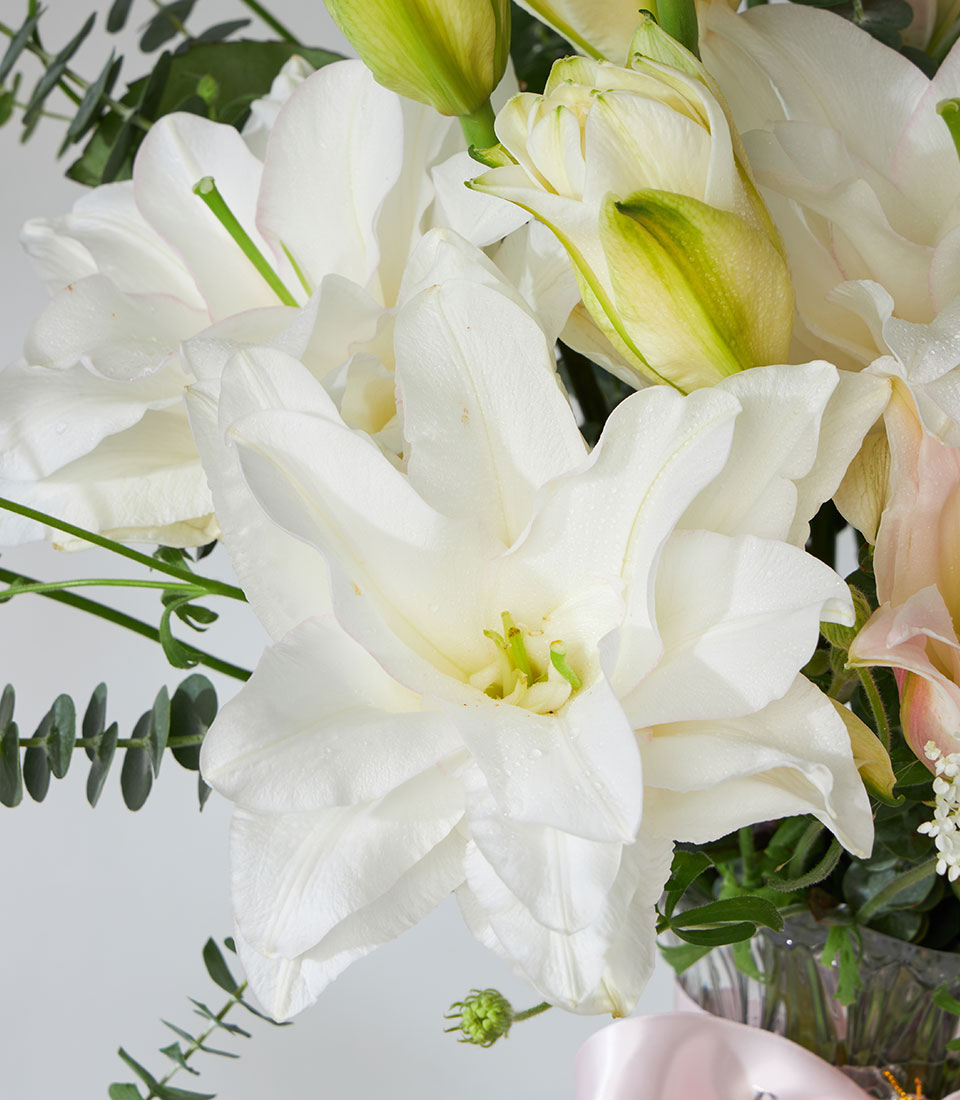 Playa Blanca white lilies and roses in crystal wave glass vase with eucalyptus