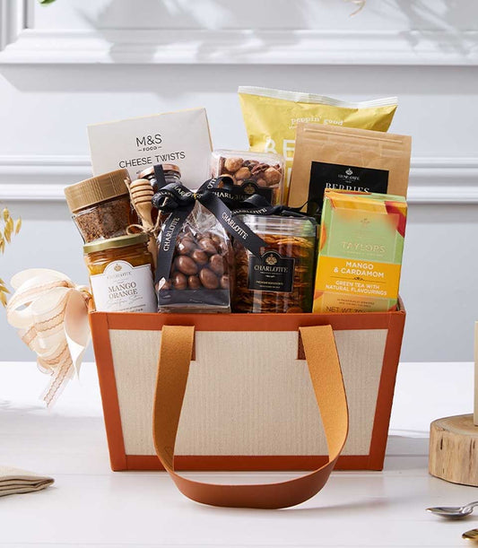 Luxury New Year gift hamper with gourmet chocolates, tea, preserves, and artisan snacks in beige leather-trim tote