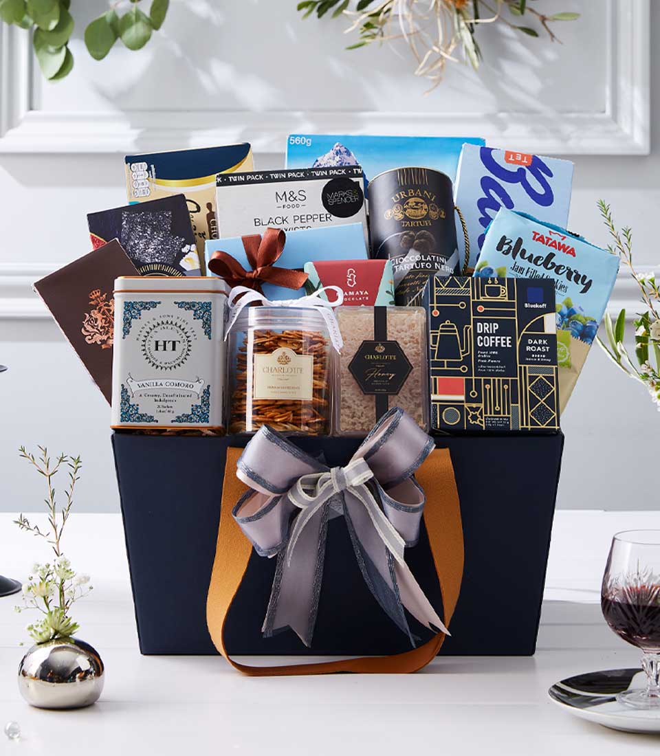 Luxury New Year gift hamper with gourmet chocolates, coffee, and tea in dark blue tote with gold lining and silver ribbon