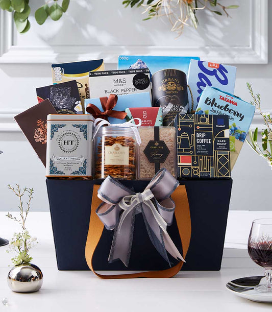 Luxury New Year gift hamper with gourmet chocolates, coffee, and tea in dark blue tote with gold lining and silver ribbon
