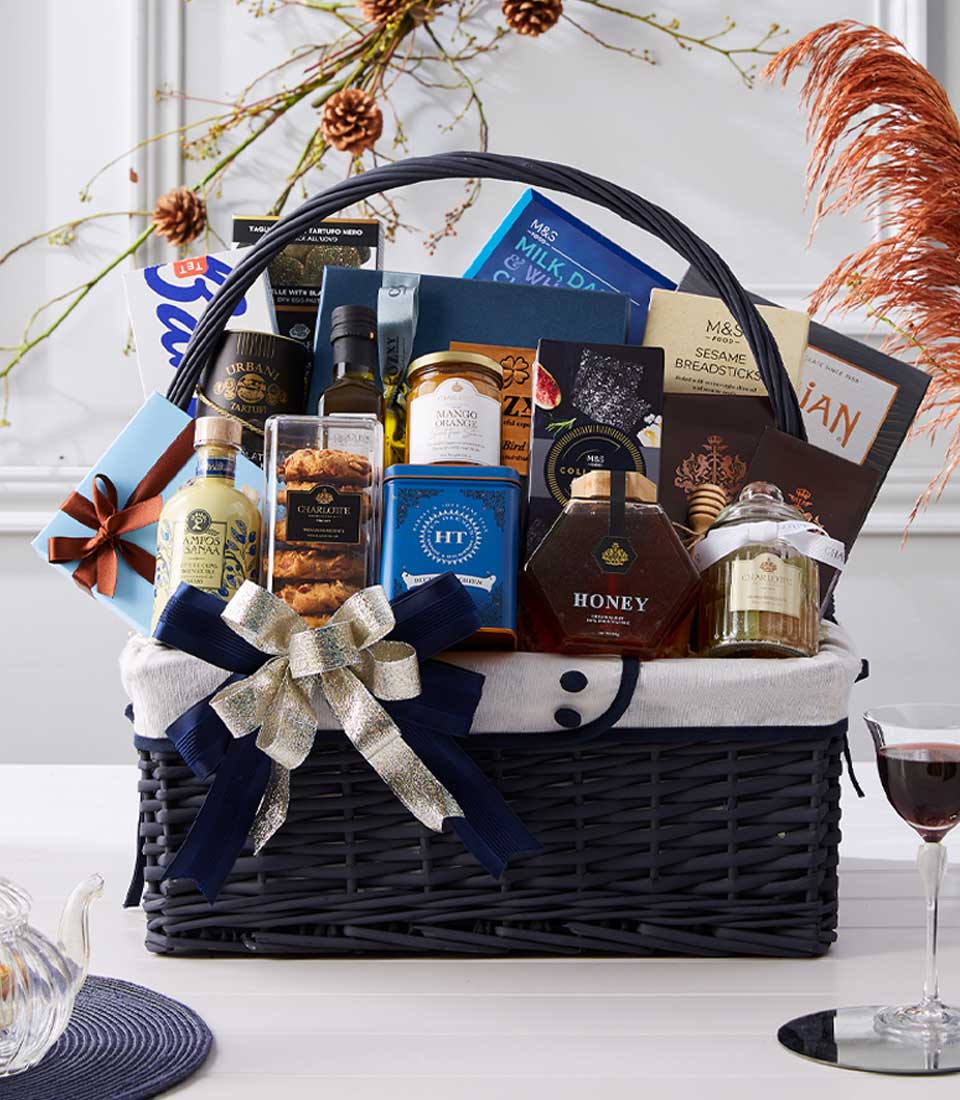 Luxury gourmet New Year gift basket with chocolates, preserves, honey, and premium imported foods in dark blue wicker