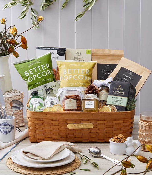 Woven wooden gift basket filled with gourmet snacks, granola, tea, and wellness treats for health-conscious gifting