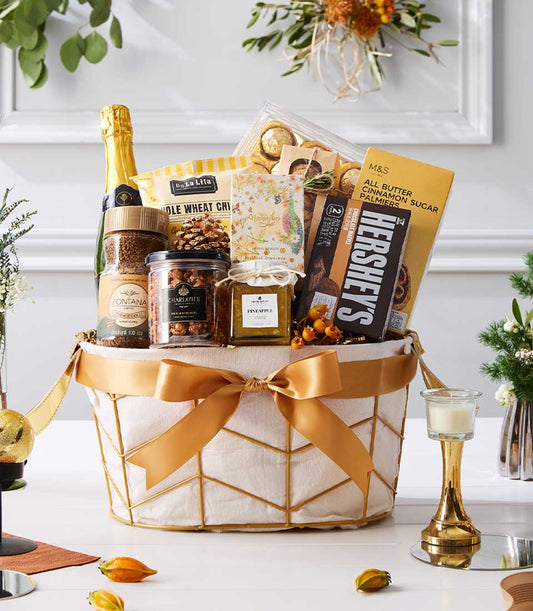 Luxury gold-trimmed wire basket with sparkling wine, gourmet coffee, chocolates, and artisan sweets for New Year gifting
