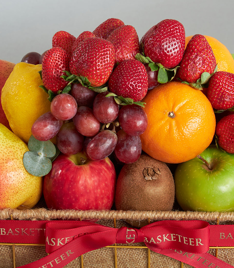 Fresh mixed fruit basket with strawberries, kiwi, grapes, and citrus in woven burlap