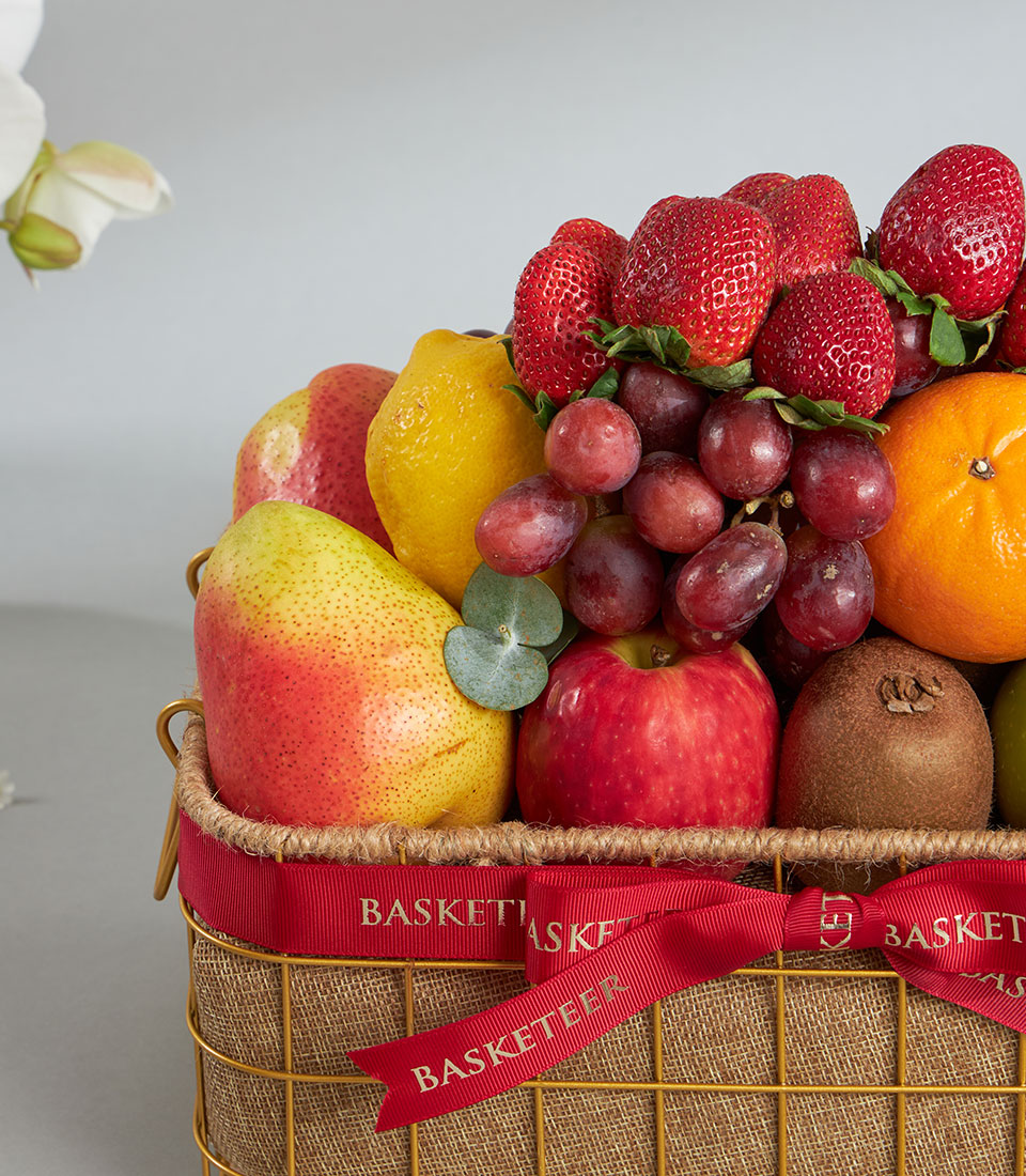 Luxury mixed fruit basket with fresh strawberries, kiwi, and imported seasonal fruits in gold wire frame