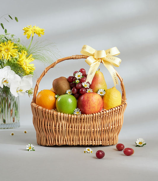 Luxury mixed fruit basket with fresh apples, oranges, kiwi, grapes and pear, tied with yellow ribbon