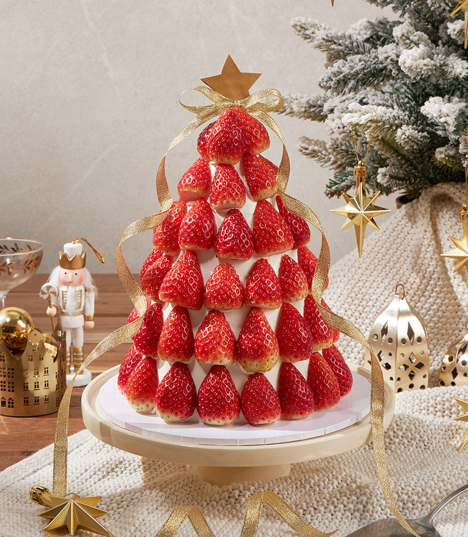 Charlotte Bakery Christmas tree artisan cake, a British-style sponge with cream cheese frosting, decorated with fresh strawberries and gold ribbon. Order custom cake Bangkok.