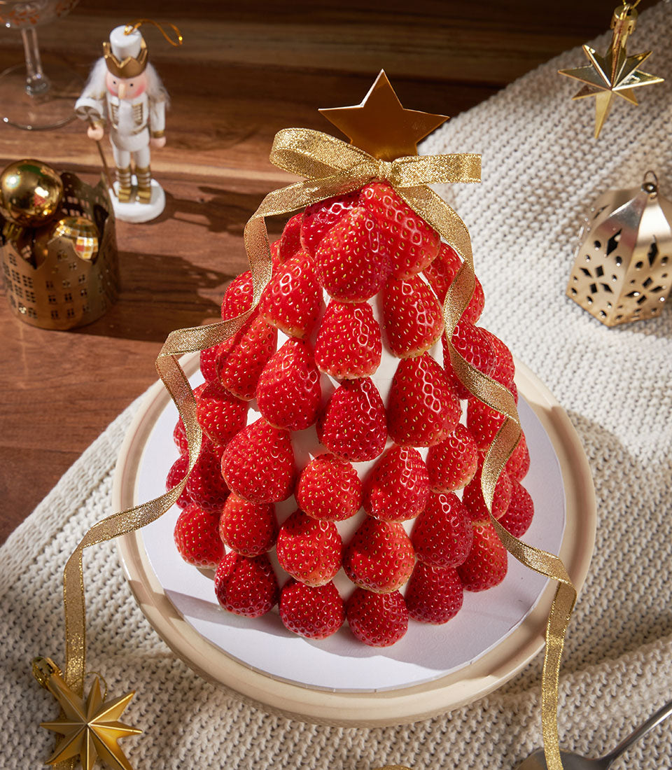 Fresh strawberry sponge Christmas tree cake with golden star and ribbon, artisan bakery gift