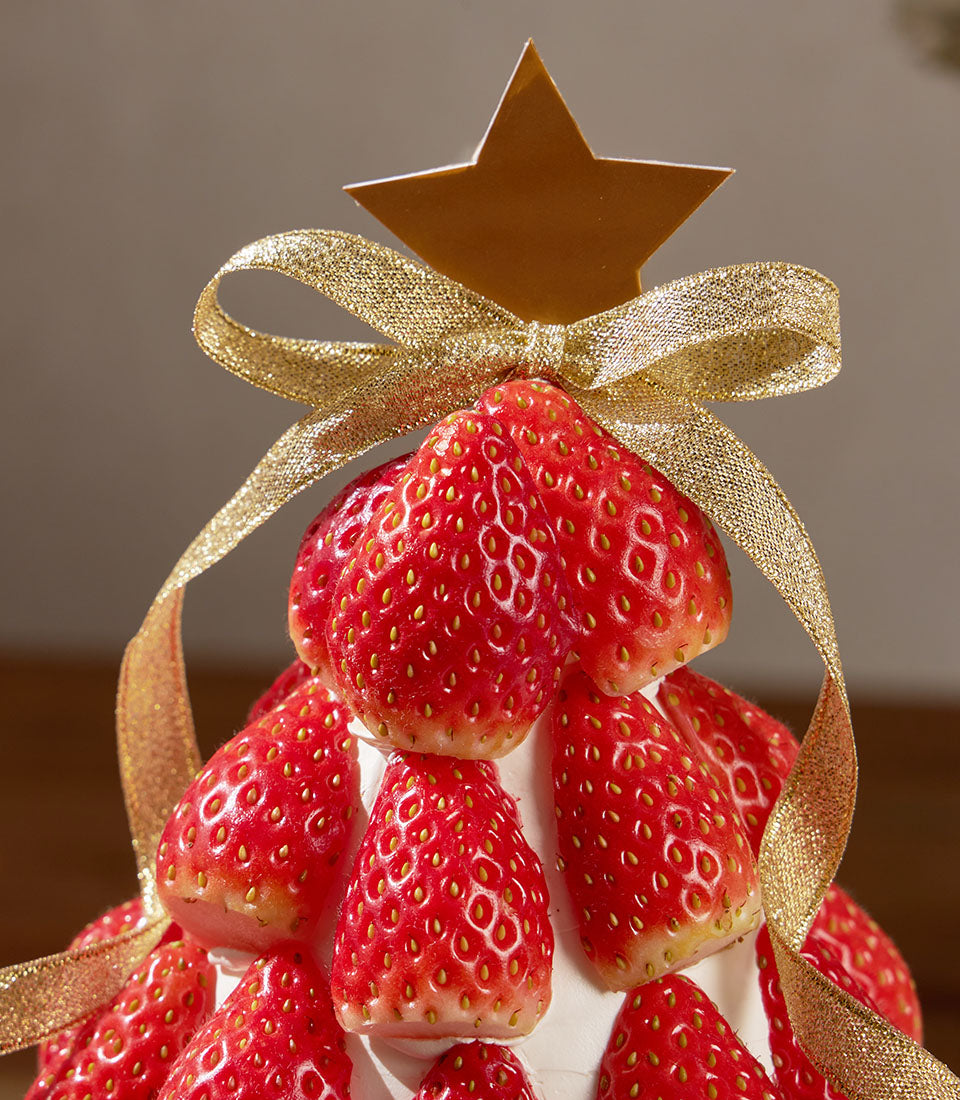 Charlotte Bakery Christmas tree cake: fresh strawberries over cream cheese frosting, gold ribbon, and star. A perfect artisan cake order in Bangkok.