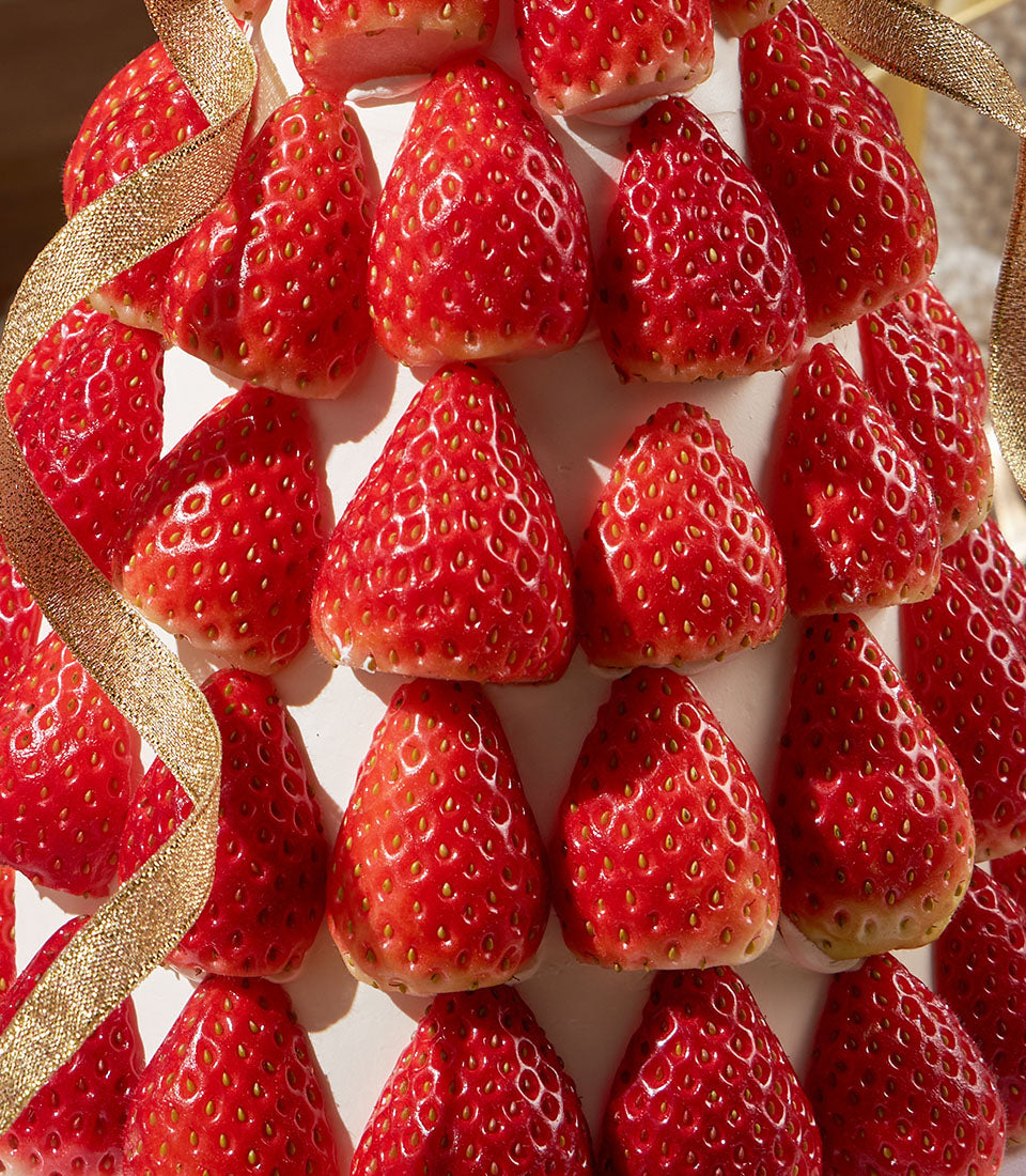 Fresh strawberry pyramid cake with gold ribbon, festive Christmas dessert tower