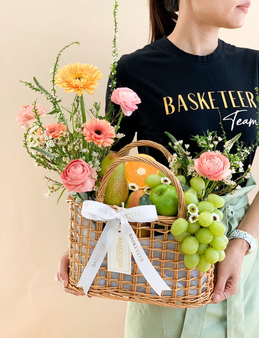 Luxury fruit and floral gift basket with pink ranunculus, gerbera daisies, fresh grapes, apples, and pears for birthdays