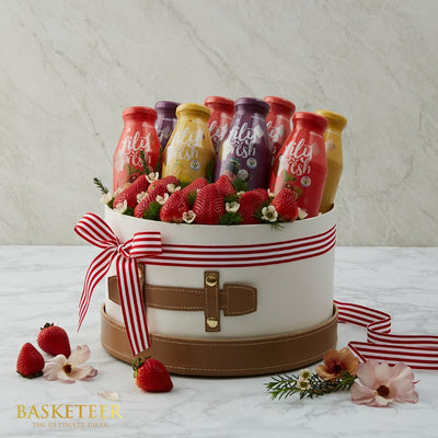 Wholesome fruits and wellness drinks gift box with strawberries, fresh juices, and flowers