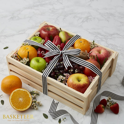 Fresh fruit get well gift basket with apples, oranges, strawberries and pomegranates in wooden crate