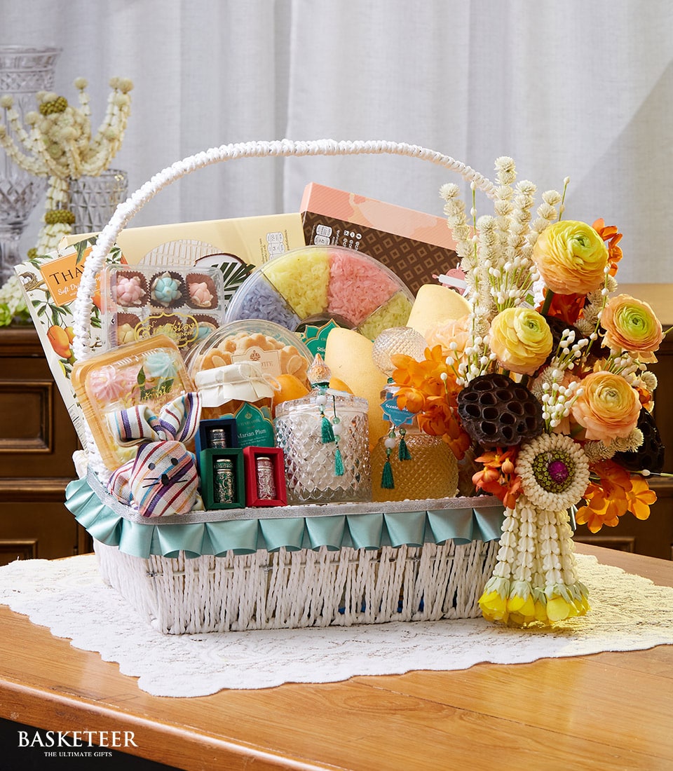Thai New Year gift basket with yellow ranunculus flowers, sticky rice, chocolates, and artisan treats in white woven basket