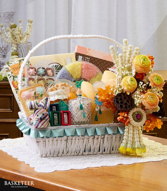 Thai New Year gift basket with yellow ranunculus flowers, sticky rice, chocolates, and artisan treats in white woven basket