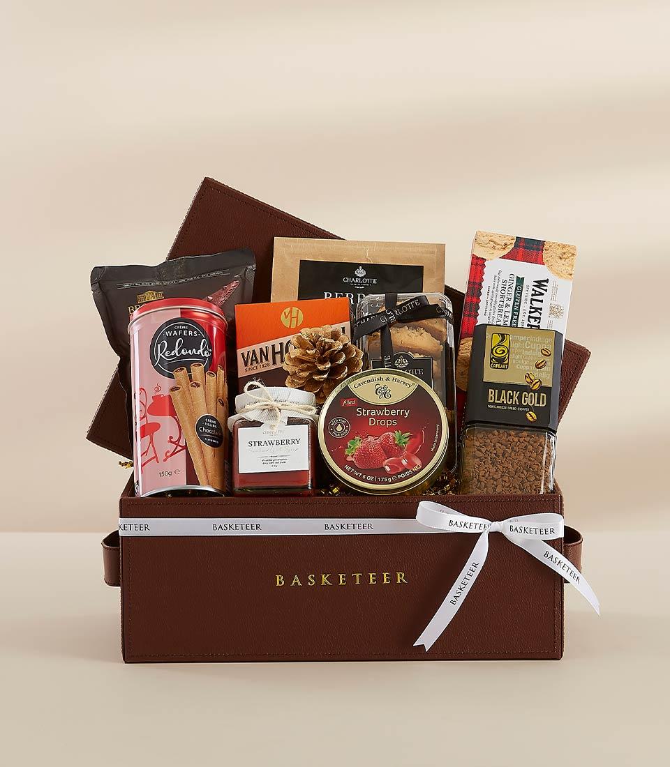 Luxury dark brown leather gift basket with gold-embossed branding, filled with gourmet treats and tied with white ribbon for
