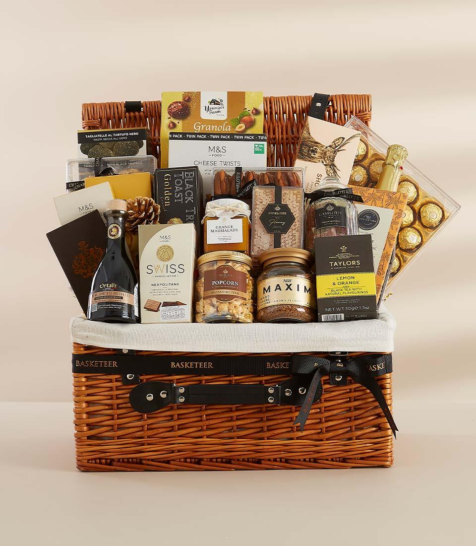 Luxury gourmet gift hamper with wicker basket, artisan chocolates, truffle pasta, marmalade, and sparkling wine