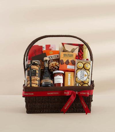 Dark brown woven gift hamper filled with gourmet chocolates, jam, biscuits, and festive treats, tied with red Basketeer