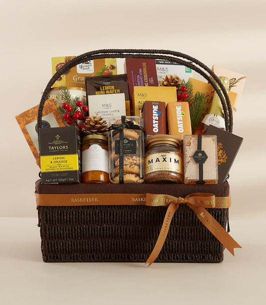 Dark brown woven luxury gift basket with gourmet treats, premium teas, jams, coffee, and artisan snacks tied with brown