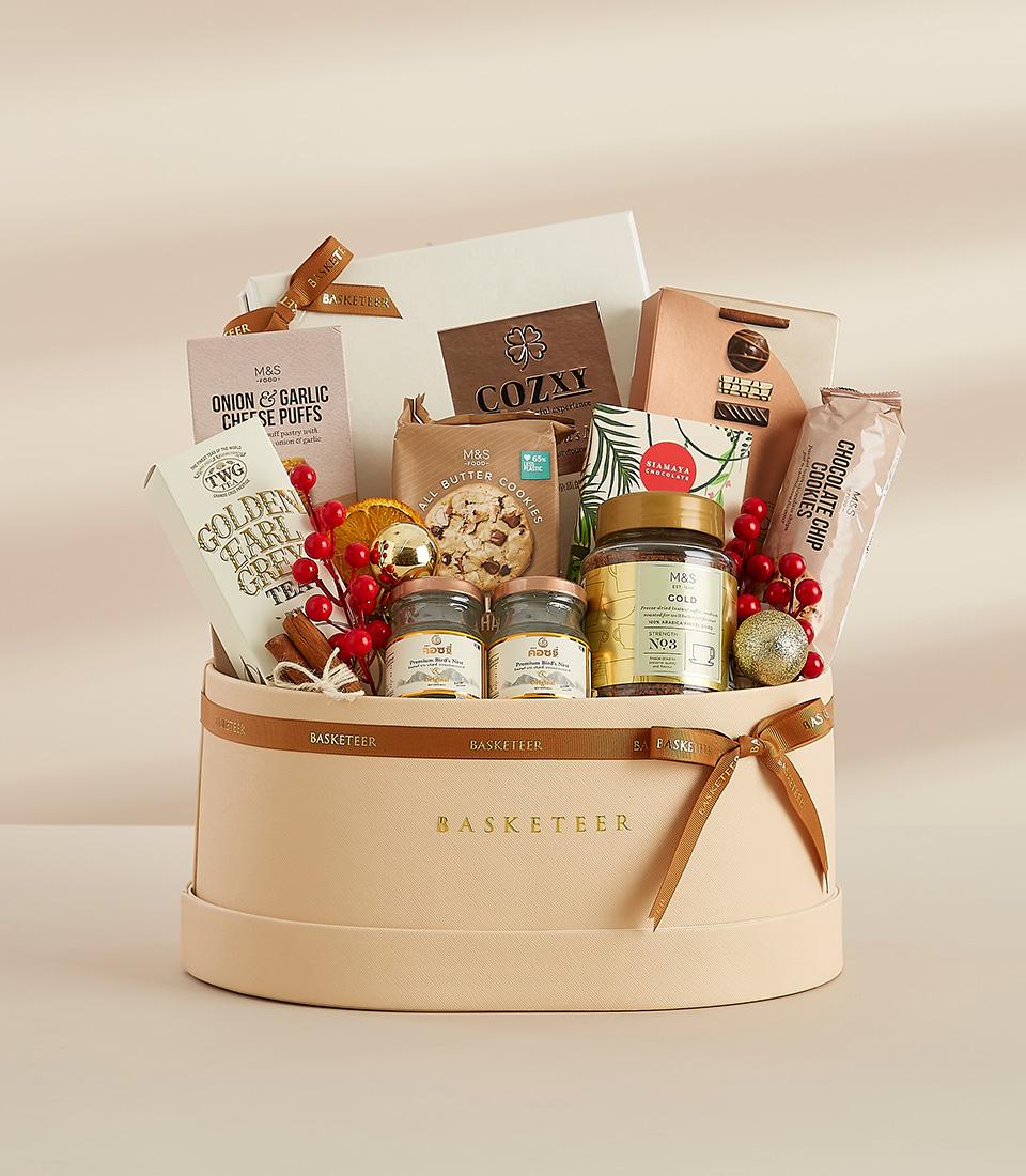 Luxury beige leather gift basket with gourmet tea, cookies, coffee, and festive gold accents