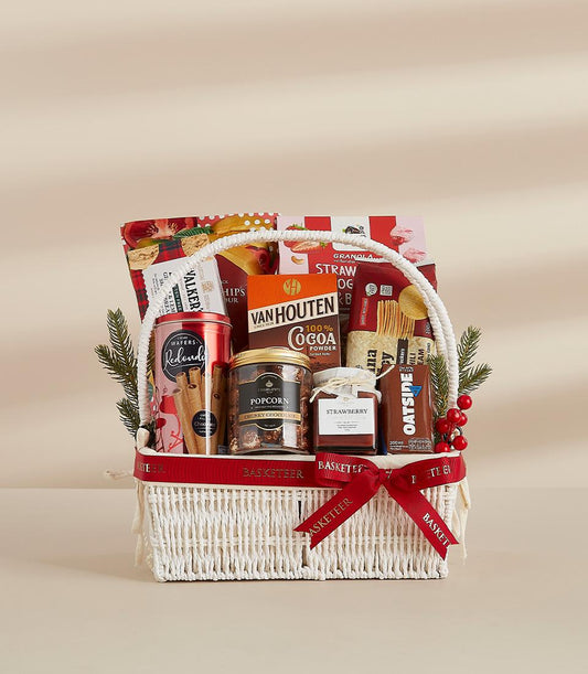 Premium white woven gift basket filled with gourmet treats, wafers, chocolate, and jam with festive red ribbon and greenery