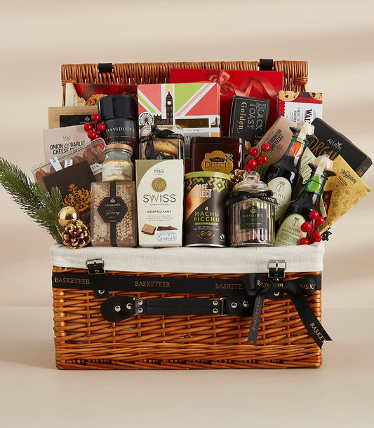 Large wicker luxury hamper filled with gourmet chocolates, preserves, coffee, and sparkling beverages with festive holiday