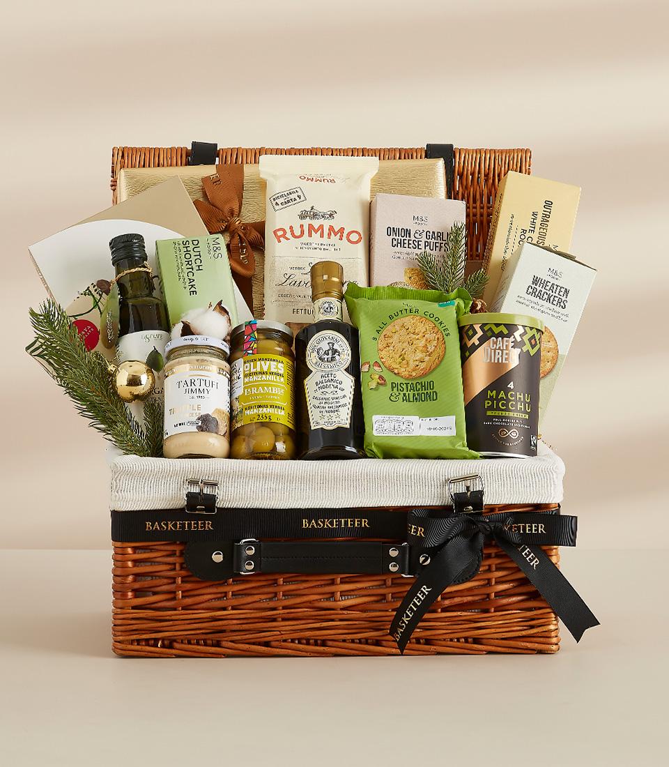 Two-tiered wicker hamper with gourmet olive oil, truffle spread, olives, balsamic glaze, cookies, coffee, pasta, and crackers