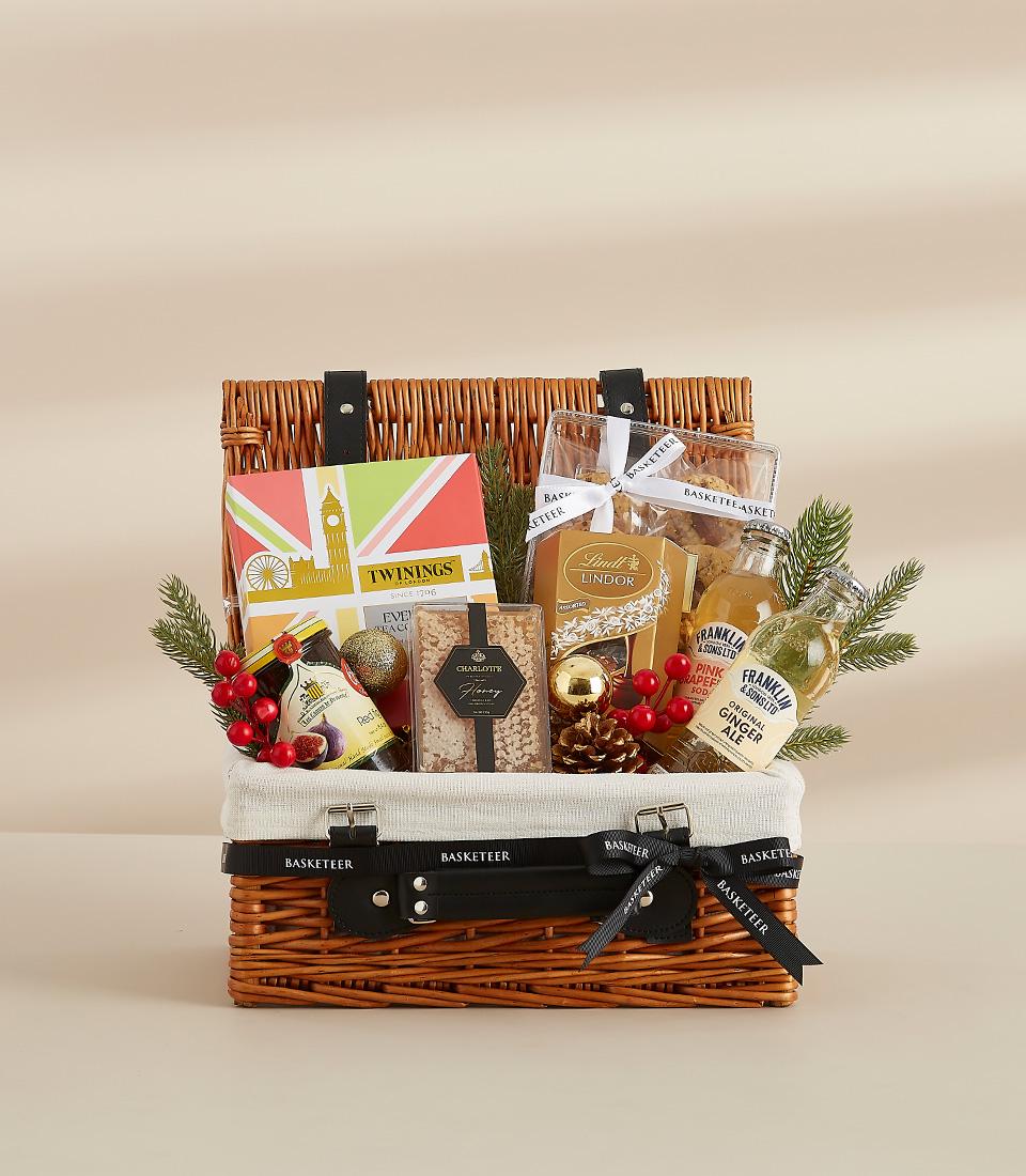 Luxury gift hamper with tea, chocolates, gourmet beverages, jam and biscuits in wicker basket with festive gold accents for