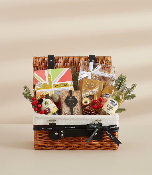 Luxury gift hamper with tea, chocolates, gourmet beverages, jam and biscuits in wicker basket with festive gold accents for