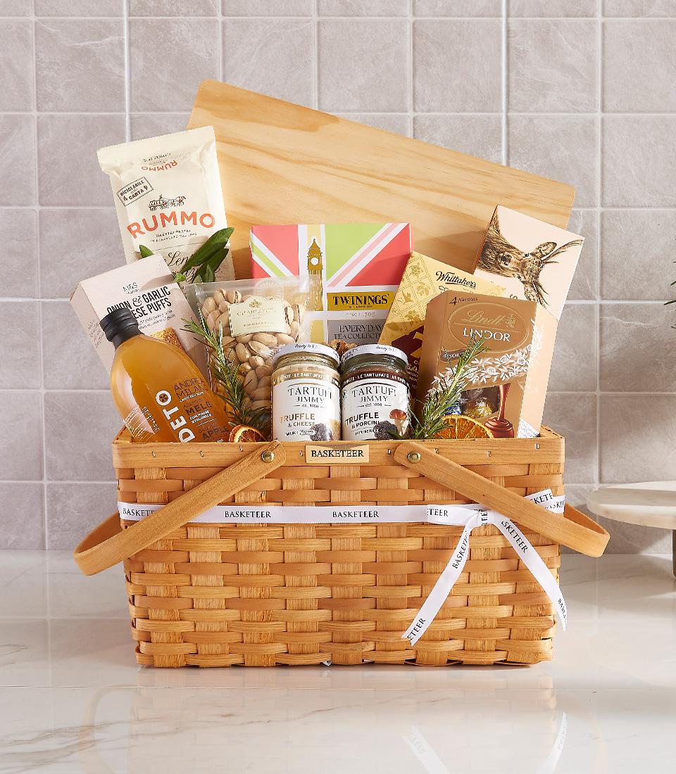 Woven light brown gift basket filled with gourmet pasta, truffle spreads, cheese puffs, pistachios, tea, chocolates, and
