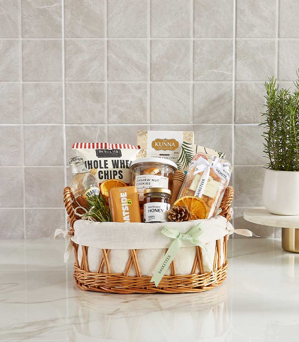 Woven wicker wellness gift basket with whole wheat chips, honey, cashew cookies, coconut snacks, and Franklin beverage, tied