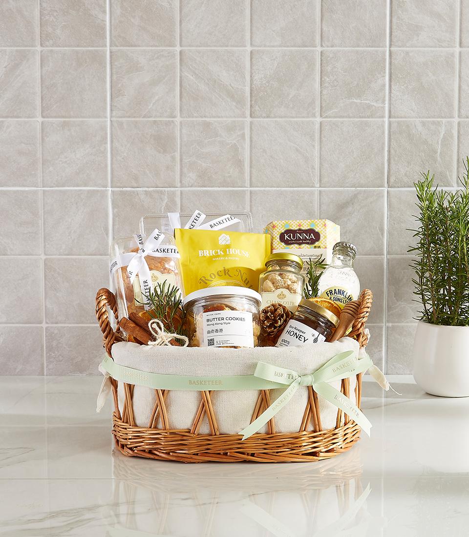 Wicker gift basket with gourmet cookies, honey, pastries, and artisan treats tied with green ribbon for New Year gifting