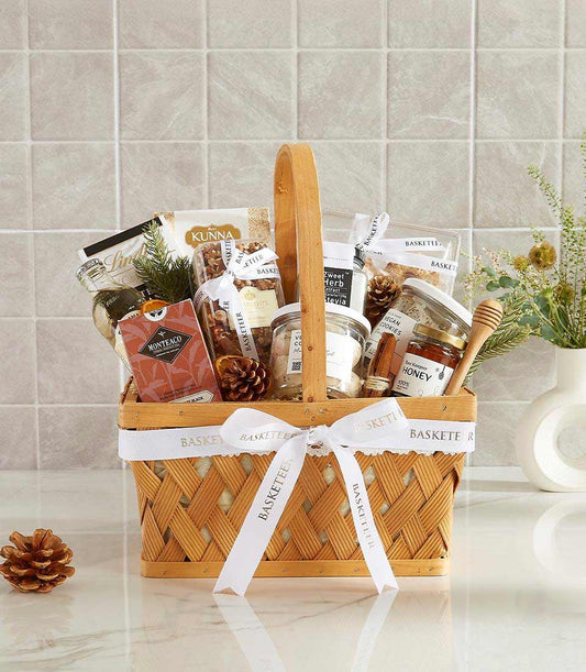 Woven wood gourmet gift basket with olive oil, tea, nuts, honey, and artisan treats tied with white ribbon