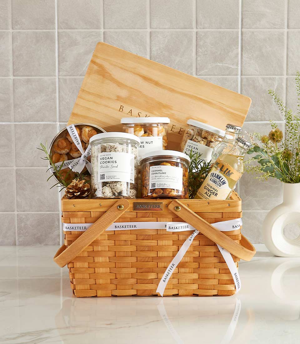 Luxury gourmet hamper with artisan cookies, caramel corn flakes, ginger ale, and fresh rosemary in woven wicker basket