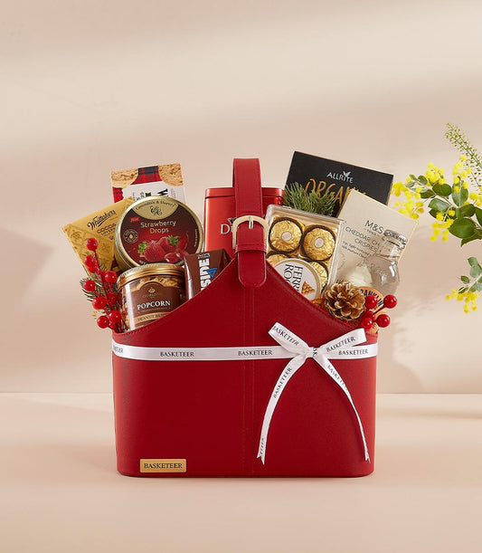 Red leather gift basket with gourmet treats, gold chocolates, and festive berries for New Year celebrations
