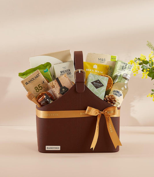 Luxury Loves brown leather gift basket with gourmet foods, honey, crackers, and gold ribbon bow for New Year gifting