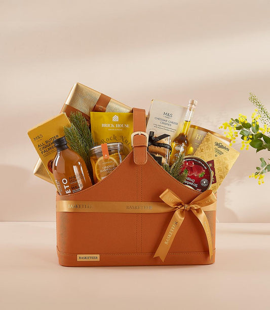 Burnt orange leather gift basket filled with gourmet treats, cheese crisps, marmalade, and artisan goods for New Year