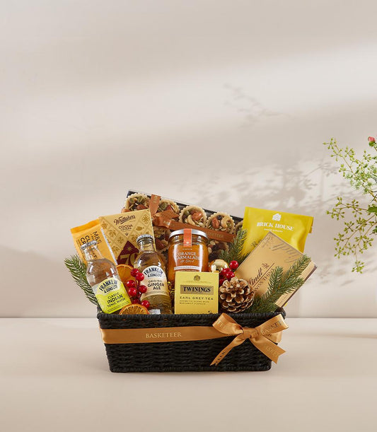 Premium gourmet gift basket with tea, marmalade, artisan pastries, and festive holiday trimmings in dark woven basket with
