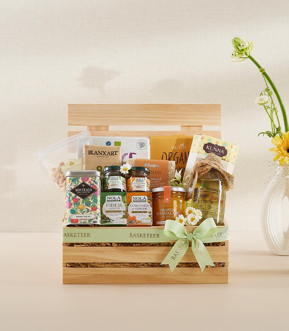 Wooden wellness gift crate with organic supplements, herbal tea, and gourmet preserves tied with green ribbon for New Year