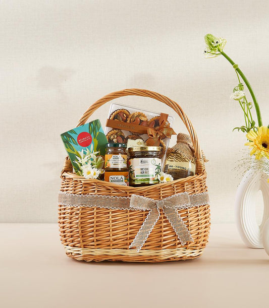 Rustic wicker gourmet gift basket with artisan spreads, coconut products, and pastries tied with burlap ribbon for New Year