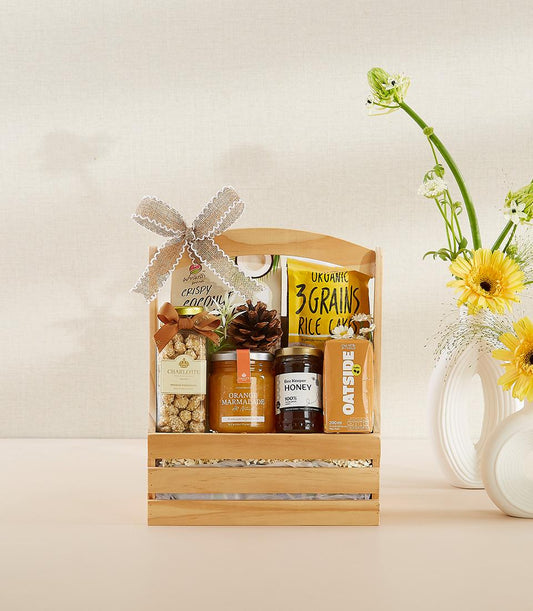 Wooden gift crate with organic wellness items, honey, biscotti, and fresh yellow gerberas for New Year gifting