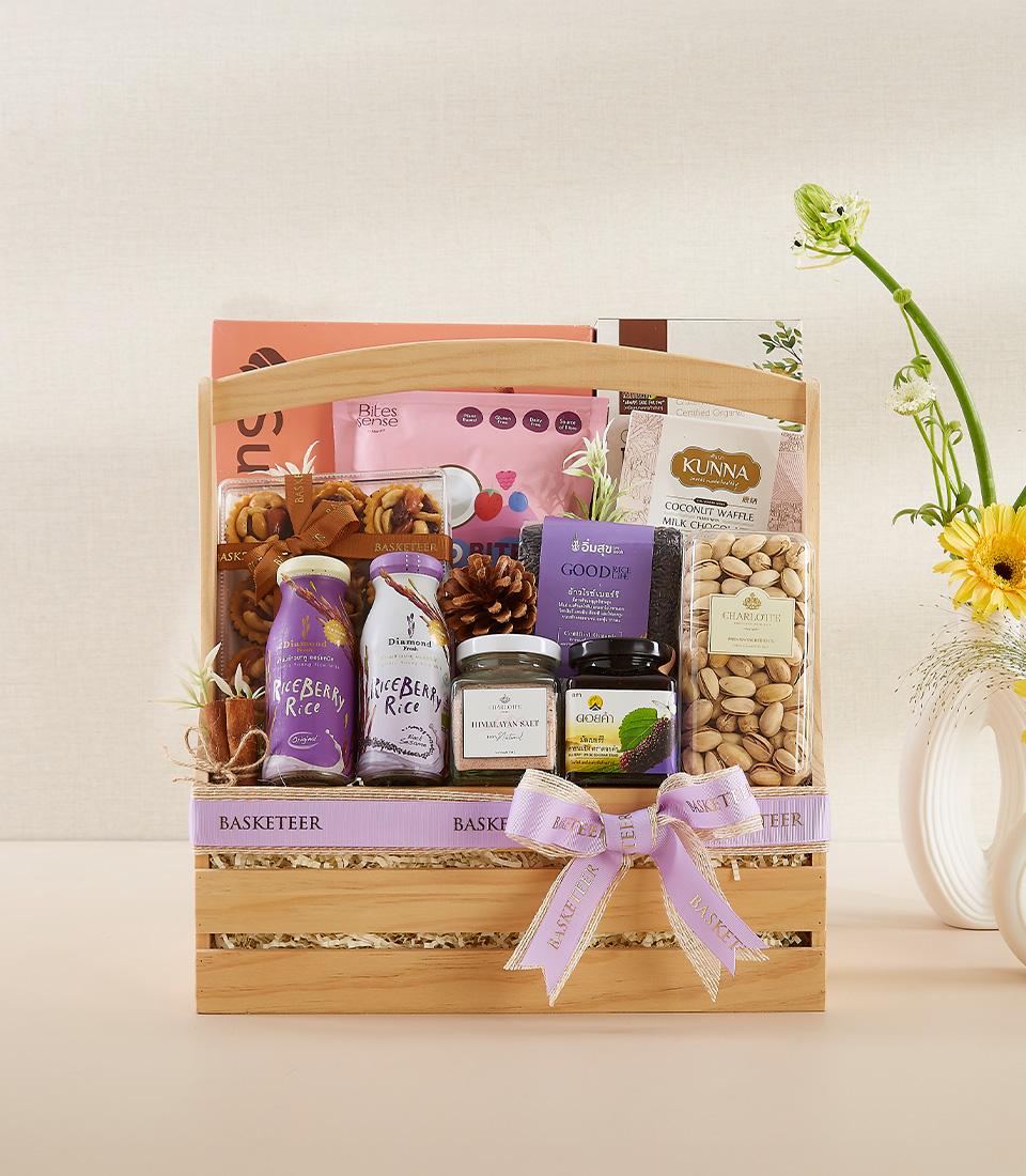 Wooden wellness gift basket with riceberry drinks, coconut waffle treats, pistachios, and Himalayan salt for New Year