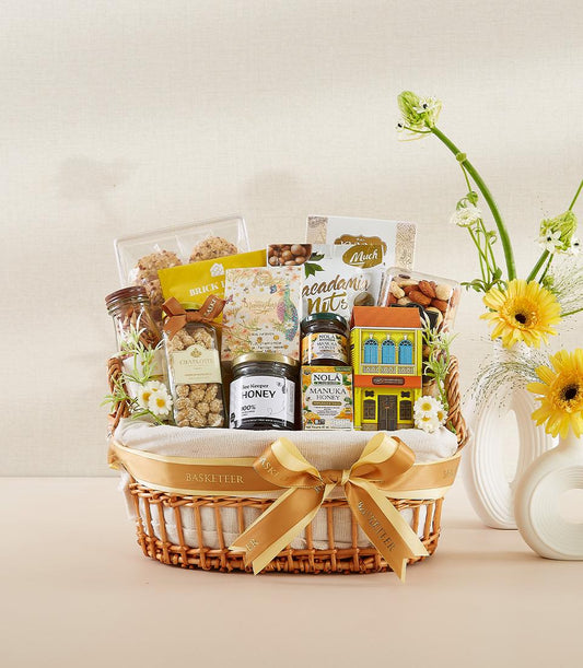 Woven wicker gourmet basket with premium honey, macadamia nuts, and artisan snacks, tied with golden ribbon