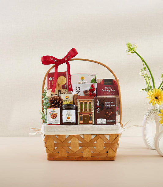 Woven wicker gift basket with rose oolong tea, chocolate coffee beans, honey, and festive decorative elements tied with red