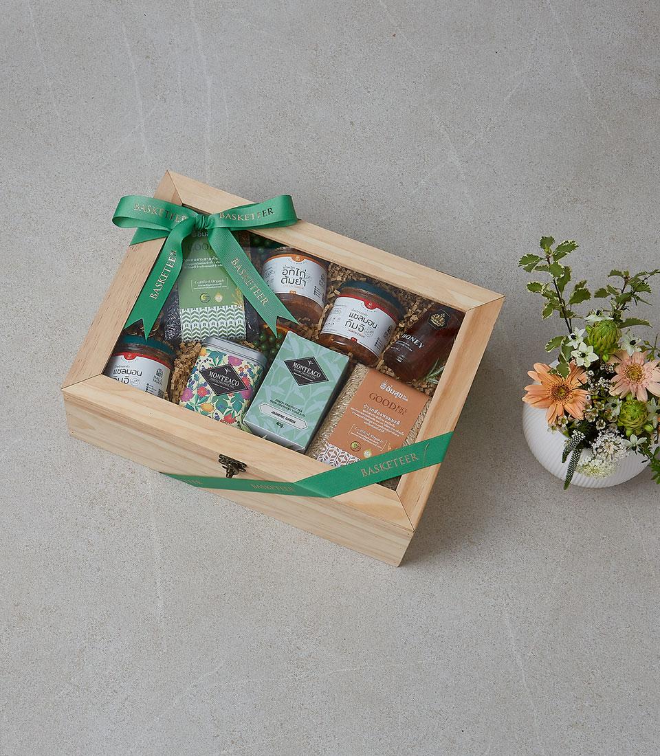 Premium wooden gift box with gourmet foods, artisan teas, honey, and fresh orange gerberas