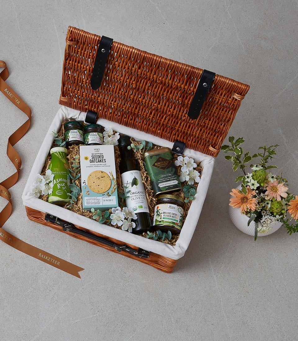 Woven picnic basket filled with gourmet foods, olive oil, tea, and rice for season's greetings gifting